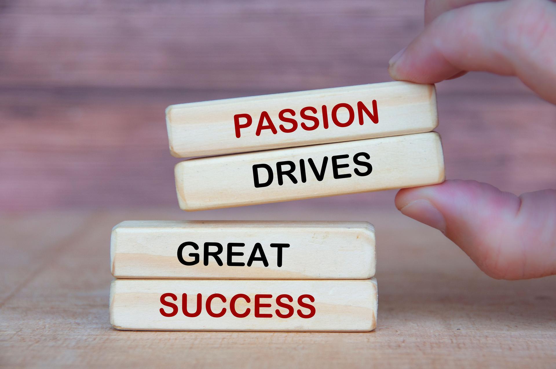 Hand holding wooden blocks with Passion Drives Great Success text on wooden blocks. Success in life concept